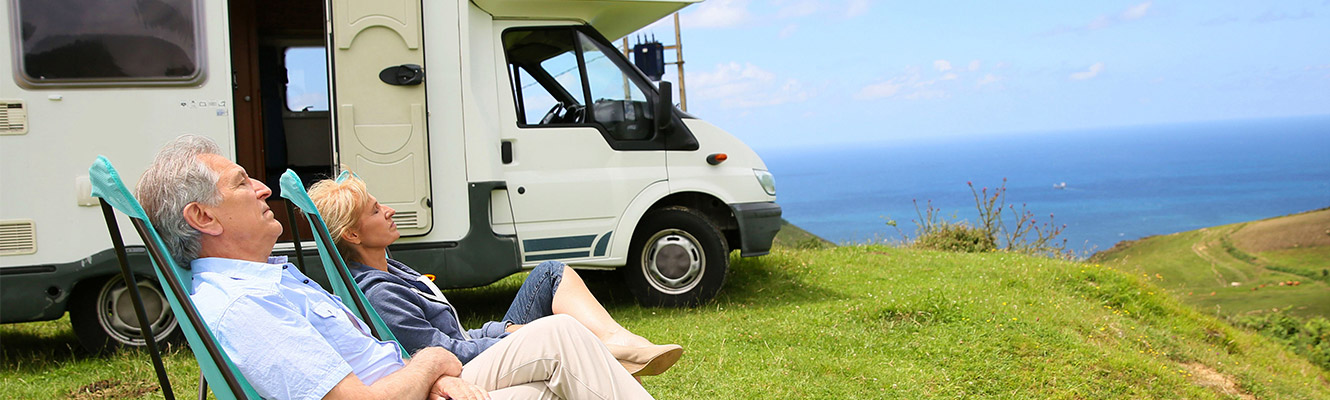 Couple sitting outside their camper enjoying the sun. 