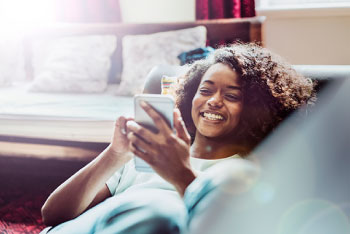 Woman using phone while laying on couch