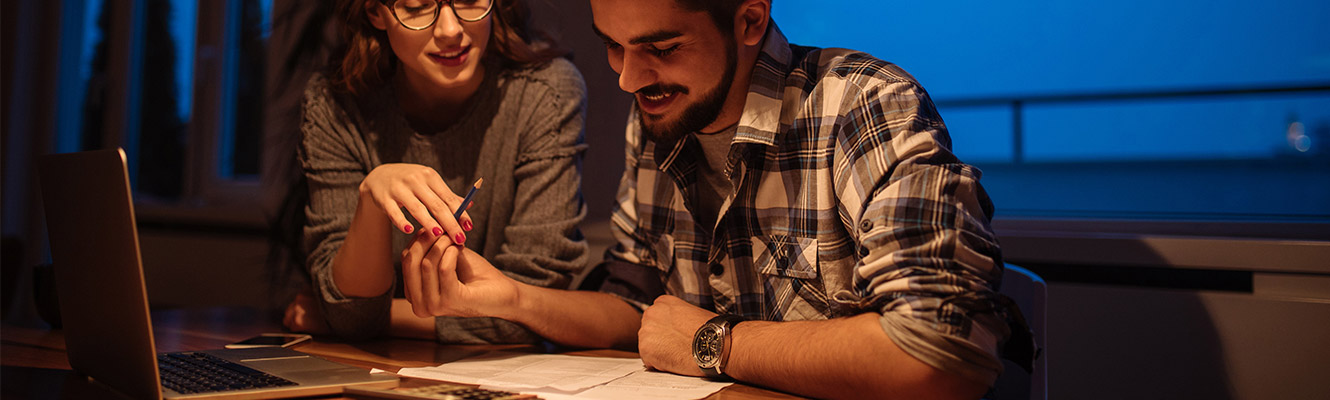 Young couple sitting at a table going over their credit bureau.