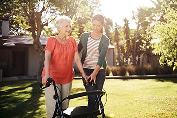 Young woman helping elderly lady with walker