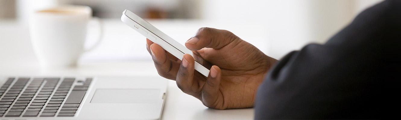 Hand holding phone in front of laptop.