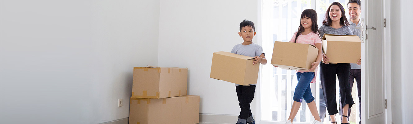 Family moving into a new house all carrying boxes. 