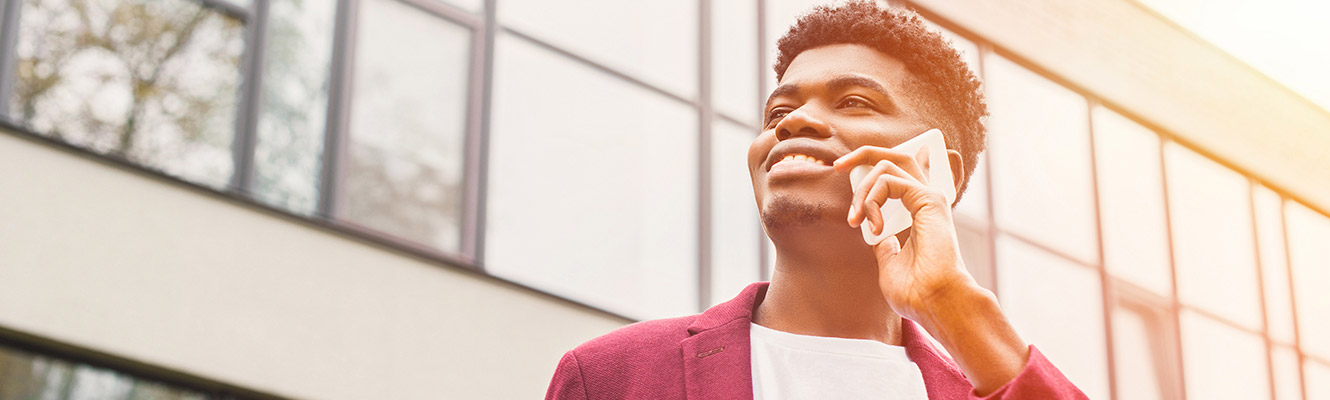 Young man sitting outside talking on phone.