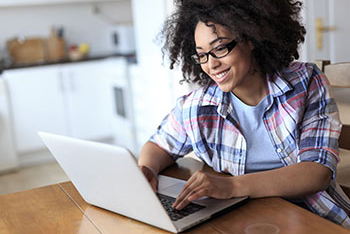 Young woman using computer in kitchen