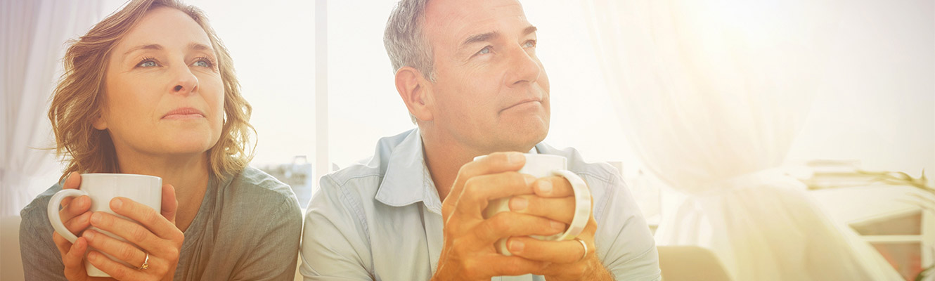 Older couple holding coffee daydreaming. 