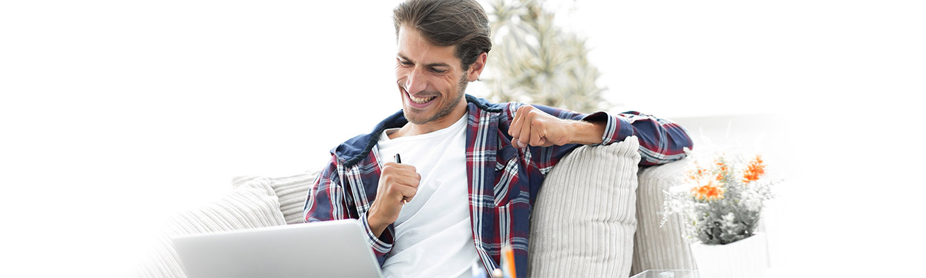 Man sitting on couch with laptop in his lap. 