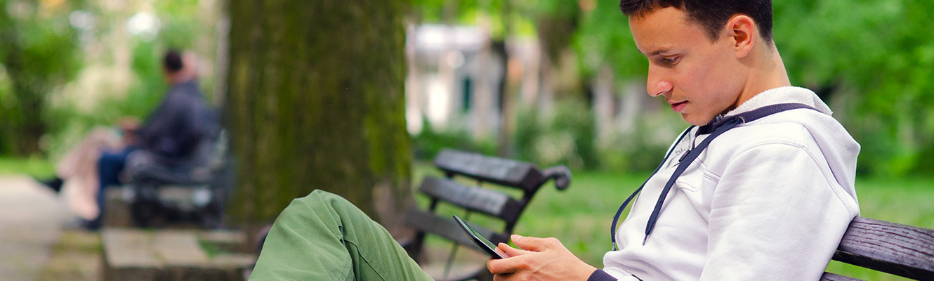 Young man sitting on bench looking at phone.