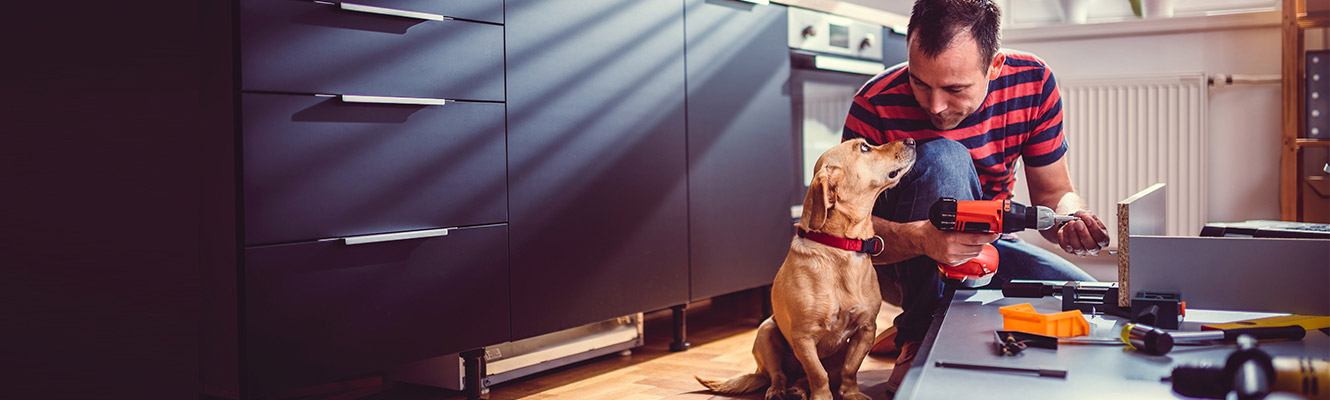 Man holding drill while sitting with dog.