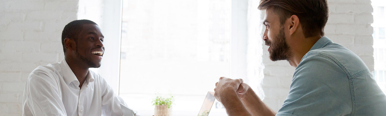 Two men sitting at a table having a discussion.